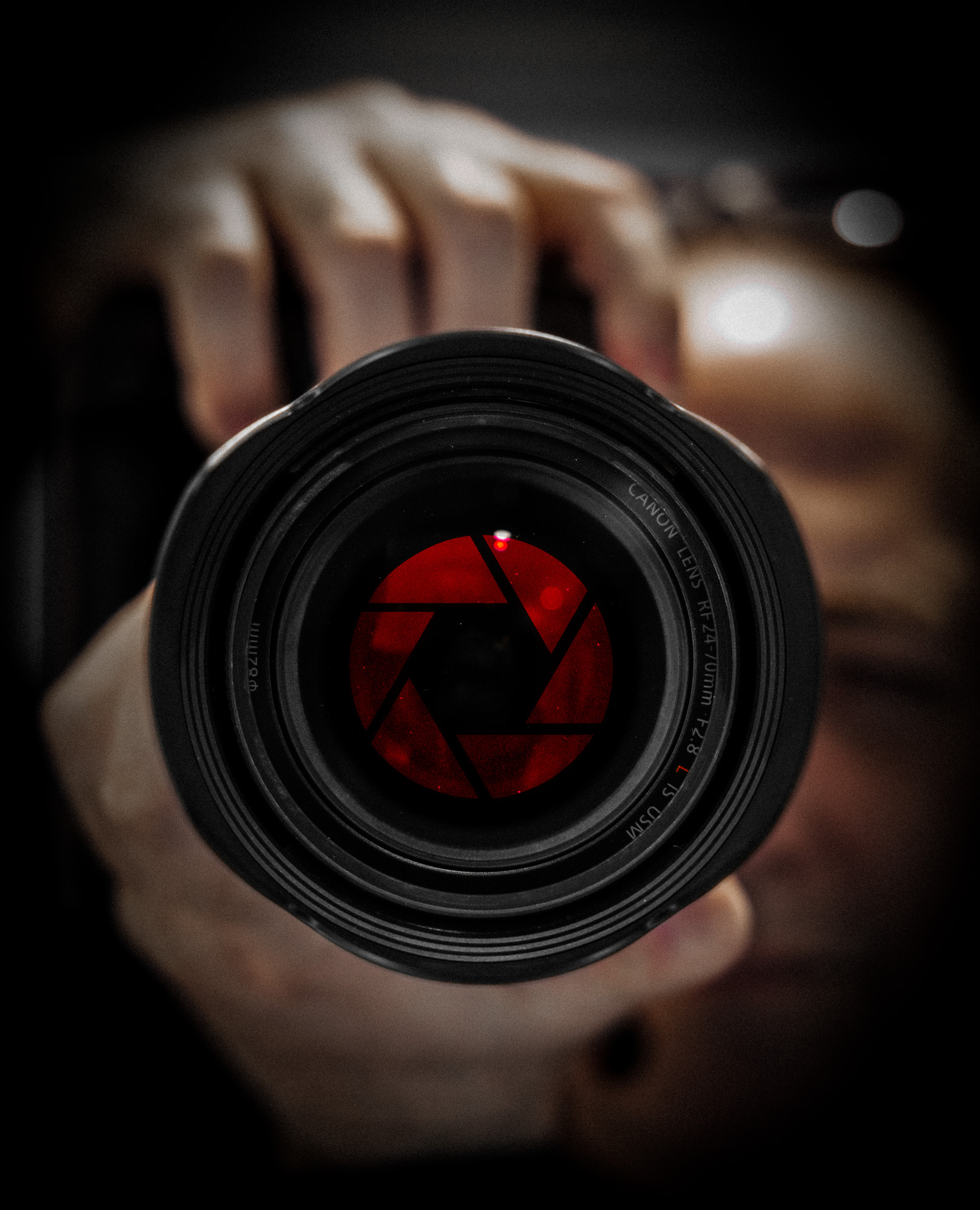 Image of Jay looking through a camera with the red lens media logo on the lens